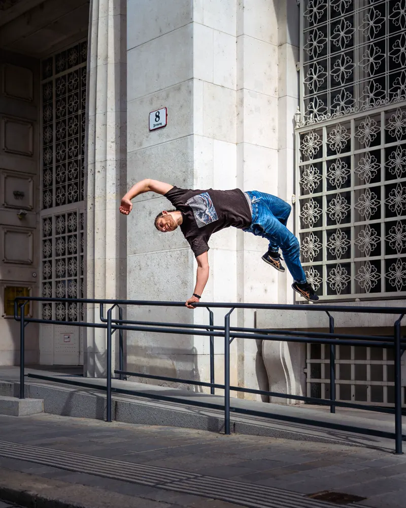 Parkour move over a railing next to a building wall