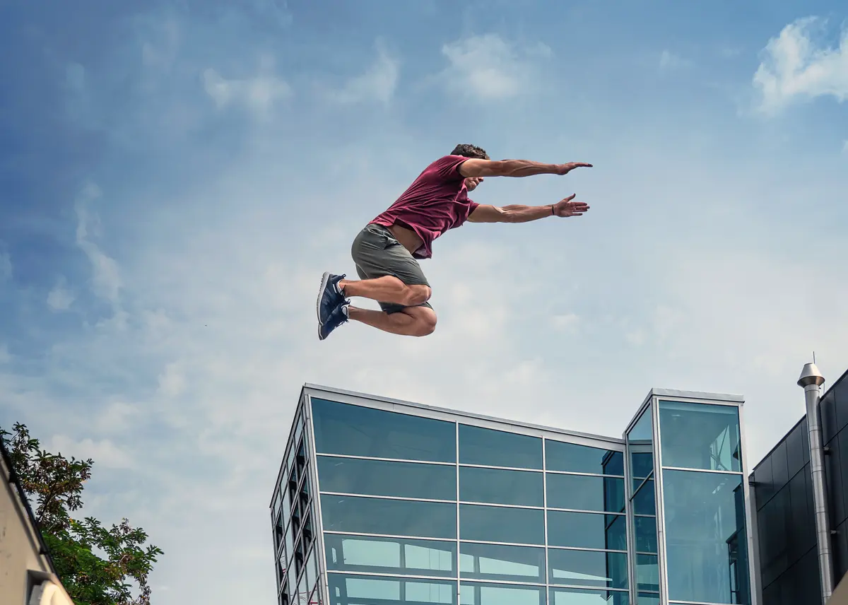 Parkour coach jumping high above the edge of a glass building in Vienna