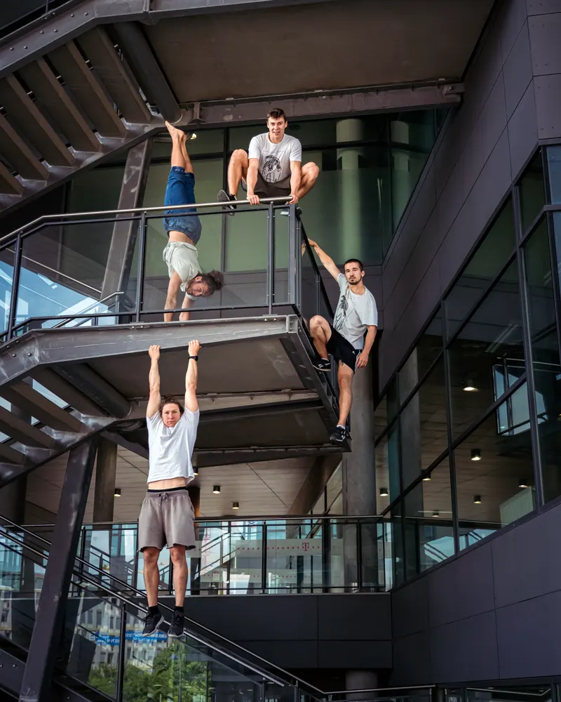 Parkour group hanging and climbing in an open steel-and-glass stairwell
